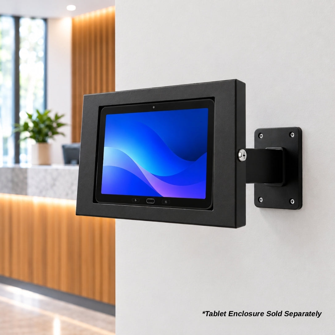 A black tablet enclosure with an attached wall mount bracket, shown mounted on a white wall in a modern office lobby. The screen displays a blue and purple abstract wallpaper.